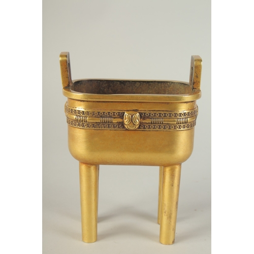 114 - A CHINESE HEAVY GILDED BRONZE TWIN HANDLE CENSER, raised on four tall legs, the base with character ... 
