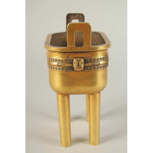 114 - A CHINESE HEAVY GILDED BRONZE TWIN HANDLE CENSER, raised on four tall legs, the base with character ... 