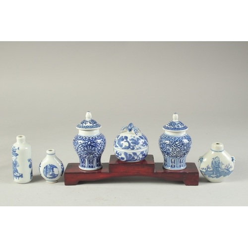 115 - THREE CHINESE BLUE AND WHITE PORCELAIN SNUFF BOTTLES on a tiered wooden stand, together with a pair ... 
