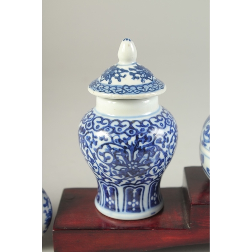115 - THREE CHINESE BLUE AND WHITE PORCELAIN SNUFF BOTTLES on a tiered wooden stand, together with a pair ... 