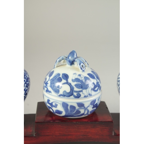 115 - THREE CHINESE BLUE AND WHITE PORCELAIN SNUFF BOTTLES on a tiered wooden stand, together with a pair ... 