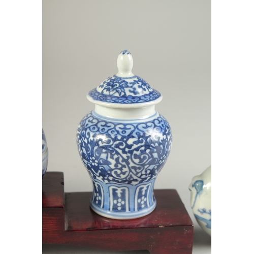 115 - THREE CHINESE BLUE AND WHITE PORCELAIN SNUFF BOTTLES on a tiered wooden stand, together with a pair ... 