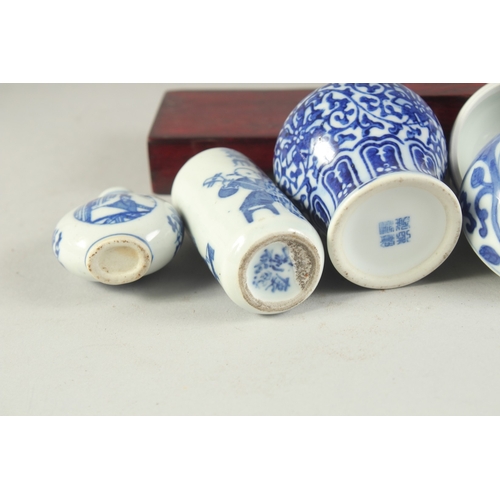 115 - THREE CHINESE BLUE AND WHITE PORCELAIN SNUFF BOTTLES on a tiered wooden stand, together with a pair ... 