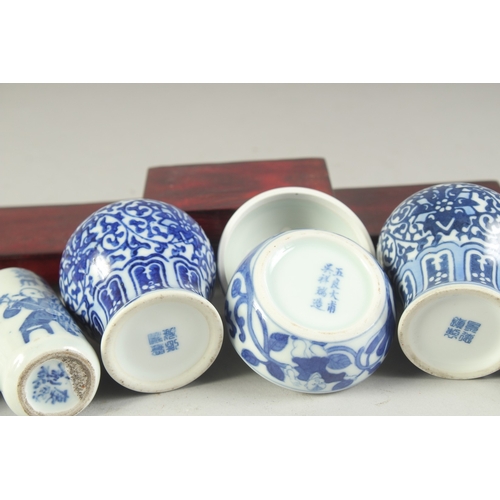 115 - THREE CHINESE BLUE AND WHITE PORCELAIN SNUFF BOTTLES on a tiered wooden stand, together with a pair ... 