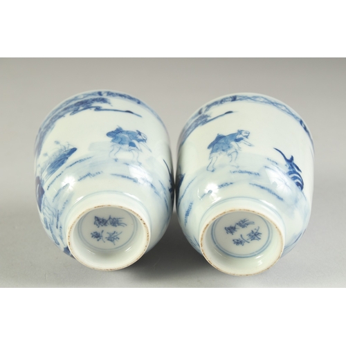116 - A PAIR OF CHINESE BLUE AND WHITE PORCELAIN CUPS, painted with a fishing scene, the bases with four-c... 