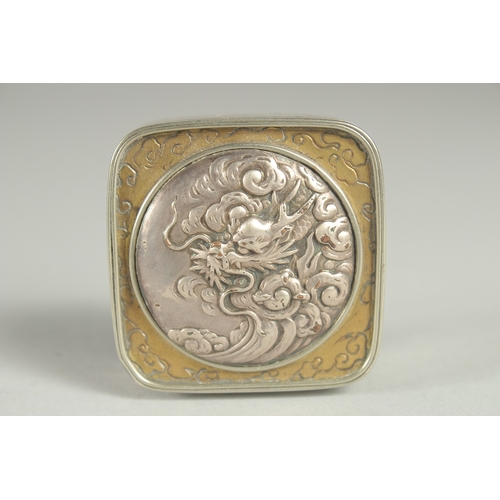 86 - A SMALL SIGNED JAPANESE WHITE METAL AND BRASS BOX, the hinged lid with relief dragon roundel, 5cm sq... 