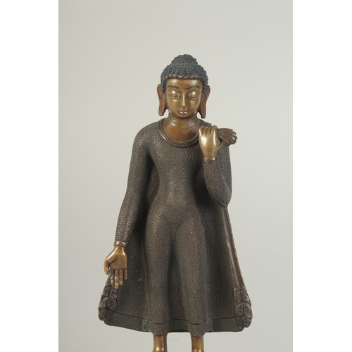 90 - A FINELY FETTLED BRONZE STANDING BUDDHA, fitted to a lotus base plinth, 21cm high.