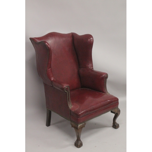 1029 - A GOOD STUDDED LEATHER WING ARM CHAIR on claw and ball feet.