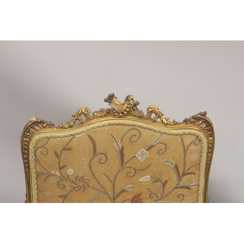 1043 - A FRENCH CARVED AND GILDED FIRE SCREEN with needlework panel. 3ft 6ins high, 2ft wide.