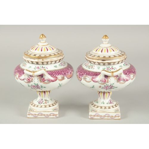 1102 - A SMALL PAIR OF SAMSON OF PARIS TWO HANDLED URNS AND COVERS with famille rose decoration and flowers... 