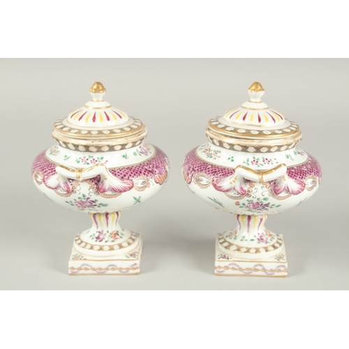 1102 - A SMALL PAIR OF SAMSON OF PARIS TWO HANDLED URNS AND COVERS with famille rose decoration and flowers... 