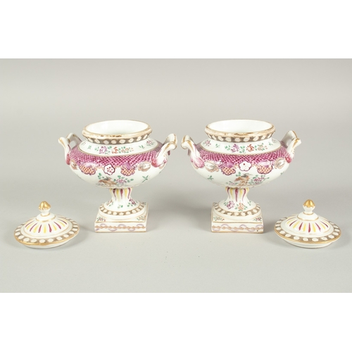 1102 - A SMALL PAIR OF SAMSON OF PARIS TWO HANDLED URNS AND COVERS with famille rose decoration and flowers... 