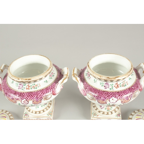 1102 - A SMALL PAIR OF SAMSON OF PARIS TWO HANDLED URNS AND COVERS with famille rose decoration and flowers... 