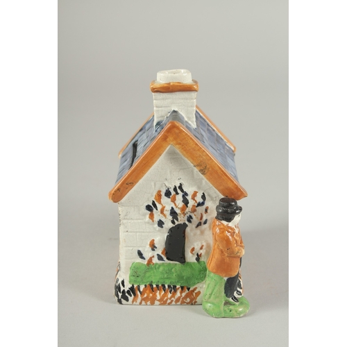 1107 - A PRATT WARE POTTERY HOUSE with blue roof, two men standing at the side of the house. 4.5ins high.... 