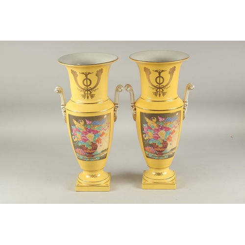 1112 - A PAIR OF SEVRES STYLE YELLOW GROUP TWO HANDLED PORCELAIN VASES with reverse panels of flowers. 1ft ... 