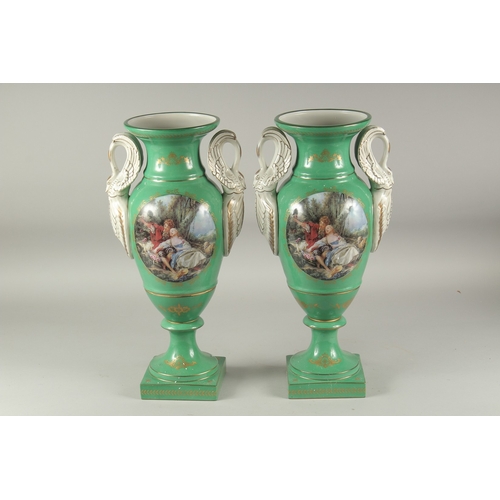 1113 - A PAIR OF SEVRES STYLE GREEN GROUP TWO HANDLED PORCELAIN VASES with swan handles and reverse classic... 