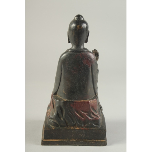 1276 - A BRONZE MODEL OF A SEATED BUDDHA one arm raised with traces of painted decoration. 9ins high.