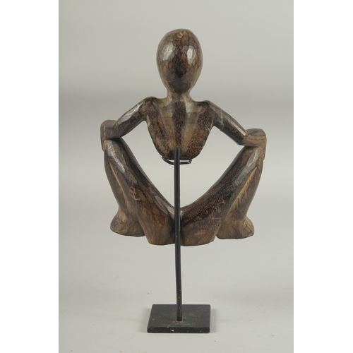 1282 - A CARVED AFRICAN OPEN WORK FIGURE. 8ins high on a metal stand.