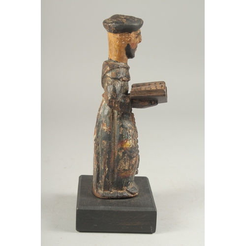 1307 - A 17TH CENTURY CARVED WOOD AND PAINTED MONK holding a book. 8ins high.