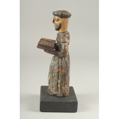 1307 - A 17TH CENTURY CARVED WOOD AND PAINTED MONK holding a book. 8ins high.