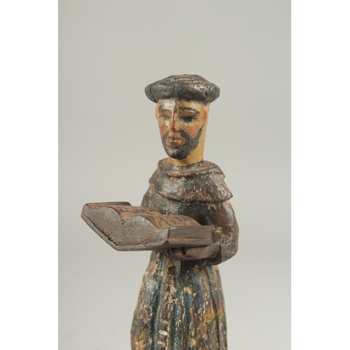 1307 - A 17TH CENTURY CARVED WOOD AND PAINTED MONK holding a book. 8ins high.