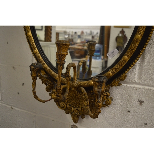 307 - A 19th century gilded and ebonised oval girandole mirror (faults).