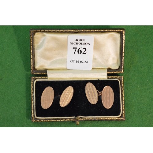 762 - A pair of 9 carat gold oval shaped cufflinks with engine turned decoration.