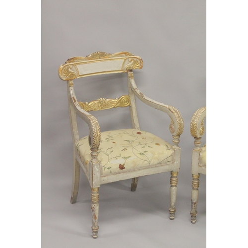 1034D - A PAIR OF CARVED, PAINTED AND PARCEL GILDED OPEN ARMCHAIRS, with floral upholstered overstuffed seat... 