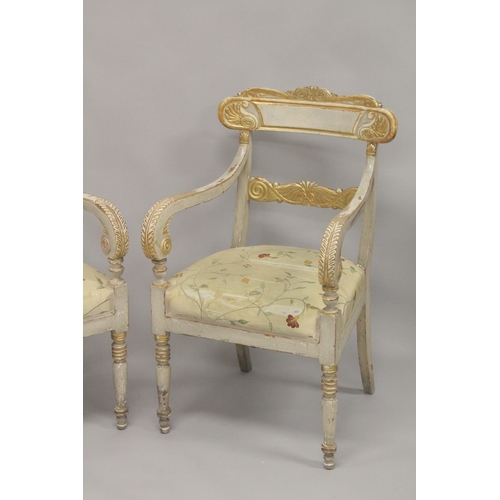 1034D - A PAIR OF CARVED, PAINTED AND PARCEL GILDED OPEN ARMCHAIRS, with floral upholstered overstuffed seat... 