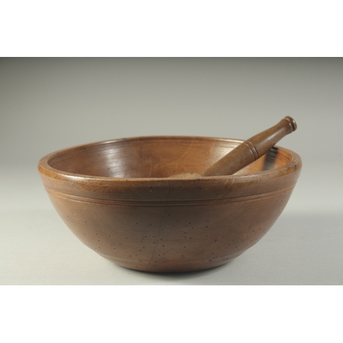 A LARGE WOODEN CIRCULAR BUTTER BOWL AND SPOON. 10ins diameter.