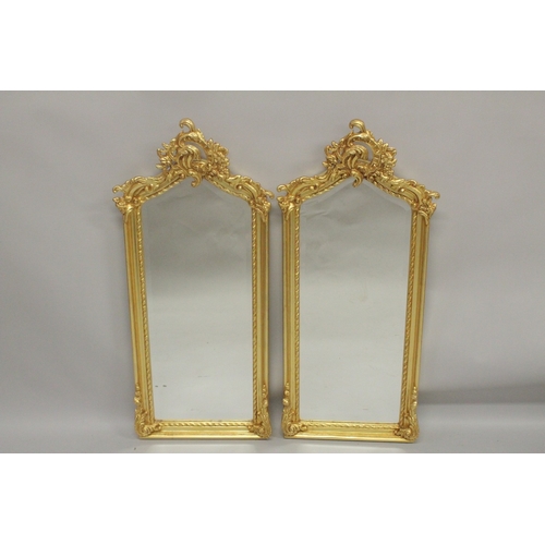 1011 - A SMALL PAIR OF GILTWOOD NARROW MIRRORS with scroll tops. 3ft 9ins high x 1ft 2ins wide.