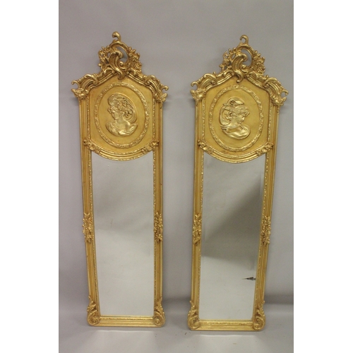 1033 - A PAIR OF DECORATIVE GILT FRAMED NARROW MIRRORS, the upper panels depicting female busts. 5ft 10ins ... 