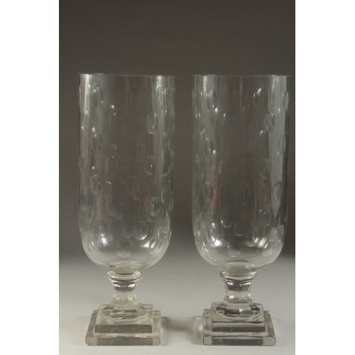 1052 - A PAIR OF GLASS STORM LANTERNS on square stepped bases. 16ins high.