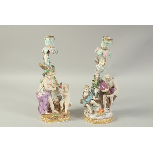 1076 - A PAIR OF MEISSEN CANDLESTICKS depicting winter and spring. 29cm high.  Cross swords mark in blue.... 