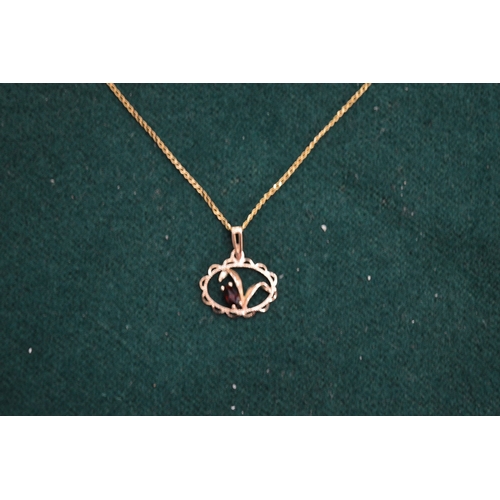 1006 - A 9ct gold chain with garnet set pendant.