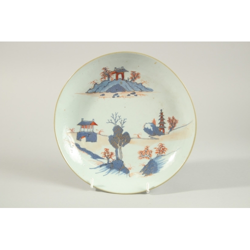 25 - AN 18TH CENTURY CHINESE BLUE AND RED PORCELAIN BOWL AND DISH, the dish painted with temples and tree... 