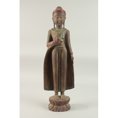 378 - AN INDIAN CARVED WOOD STANDING BUDDHA UPON A LOTUS BASE, with applied coloured glass to the robes, 6... 