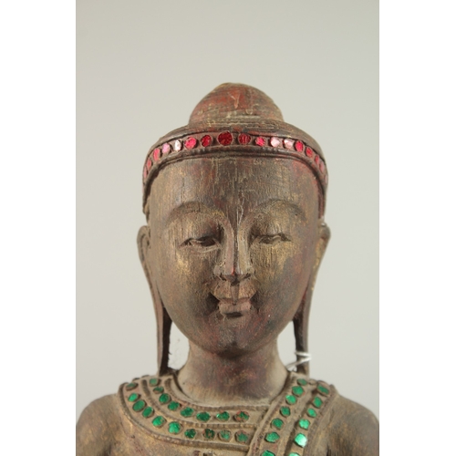 378 - AN INDIAN CARVED WOOD STANDING BUDDHA UPON A LOTUS BASE, with applied coloured glass to the robes, 6... 