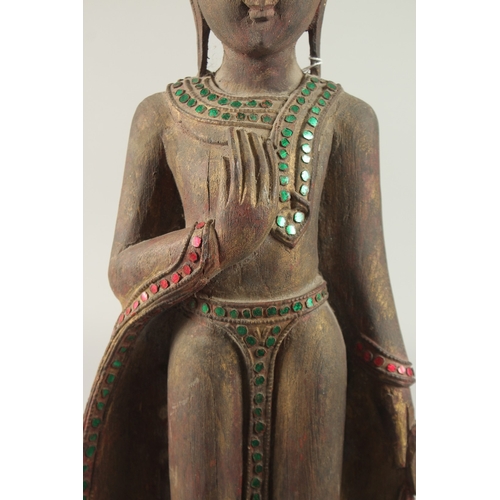 378 - AN INDIAN CARVED WOOD STANDING BUDDHA UPON A LOTUS BASE, with applied coloured glass to the robes, 6... 