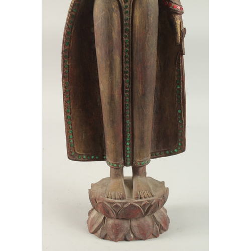 378 - AN INDIAN CARVED WOOD STANDING BUDDHA UPON A LOTUS BASE, with applied coloured glass to the robes, 6... 