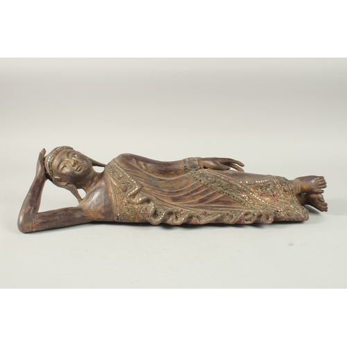 379 - AN INDIAN CARVED WOOD RECLINING BUDDHA, with inset coloured glass to the robes, 59cm long.