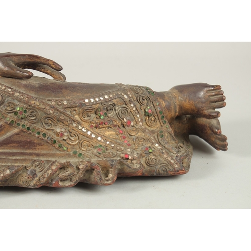 379 - AN INDIAN CARVED WOOD RECLINING BUDDHA, with inset coloured glass to the robes, 59cm long.