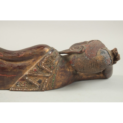 379 - AN INDIAN CARVED WOOD RECLINING BUDDHA, with inset coloured glass to the robes, 59cm long.