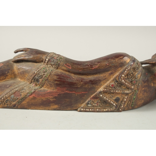 379 - AN INDIAN CARVED WOOD RECLINING BUDDHA, with inset coloured glass to the robes, 59cm long.