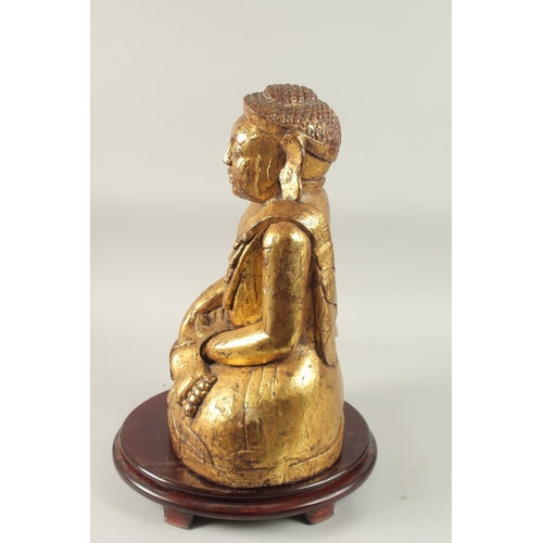 380 - A LARGE GILDED CARVED WOODEN BUDDHA WITH OVAL HARDWOOD STAND, Buddha 52cm high, base 29cm wide, wood... 