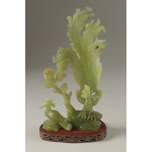 4 - A CHINESE CARVED JADE GROUP ON HARDWOOD STAND, carved in the form of a peacock and pea hen on a rock... 