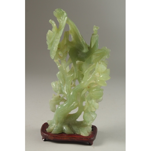 5 - A CHINESE CARVED JADE GROUP ON HARDWOOD STAND, carved with a peacock elevated on a large floral reli... 