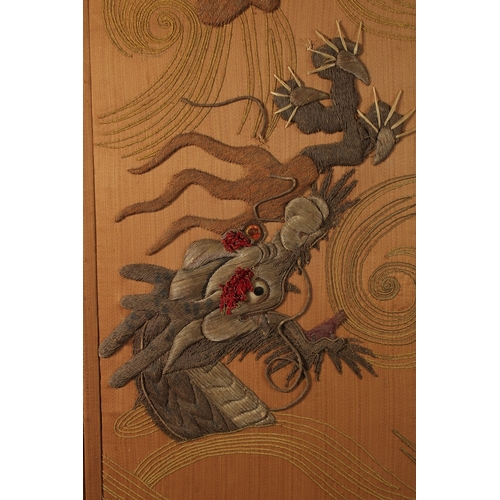 86 - A CHINESE FOUR PANEL EMBROIDERED AND PADDED SILK OVERLAID SCREEN, depicting two dragons amongst swir... 