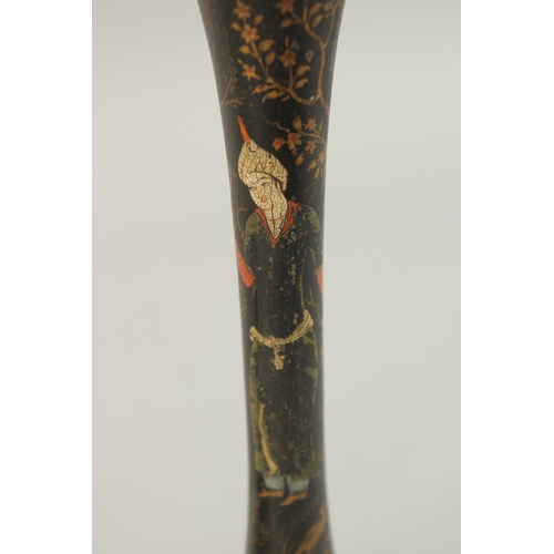 315 - A PAIR OF PERSIAN QAJAR LACQUERED WOOD CANDLESTICKS, decorated with figures and flora, 26.5cm high.