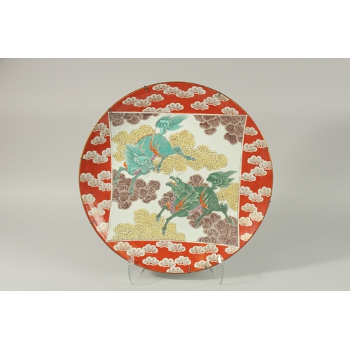 56 - A FINE CHINESE RED GROUND PORCELAIN CHARGER, painted with central panel depicting two mythical beast... 